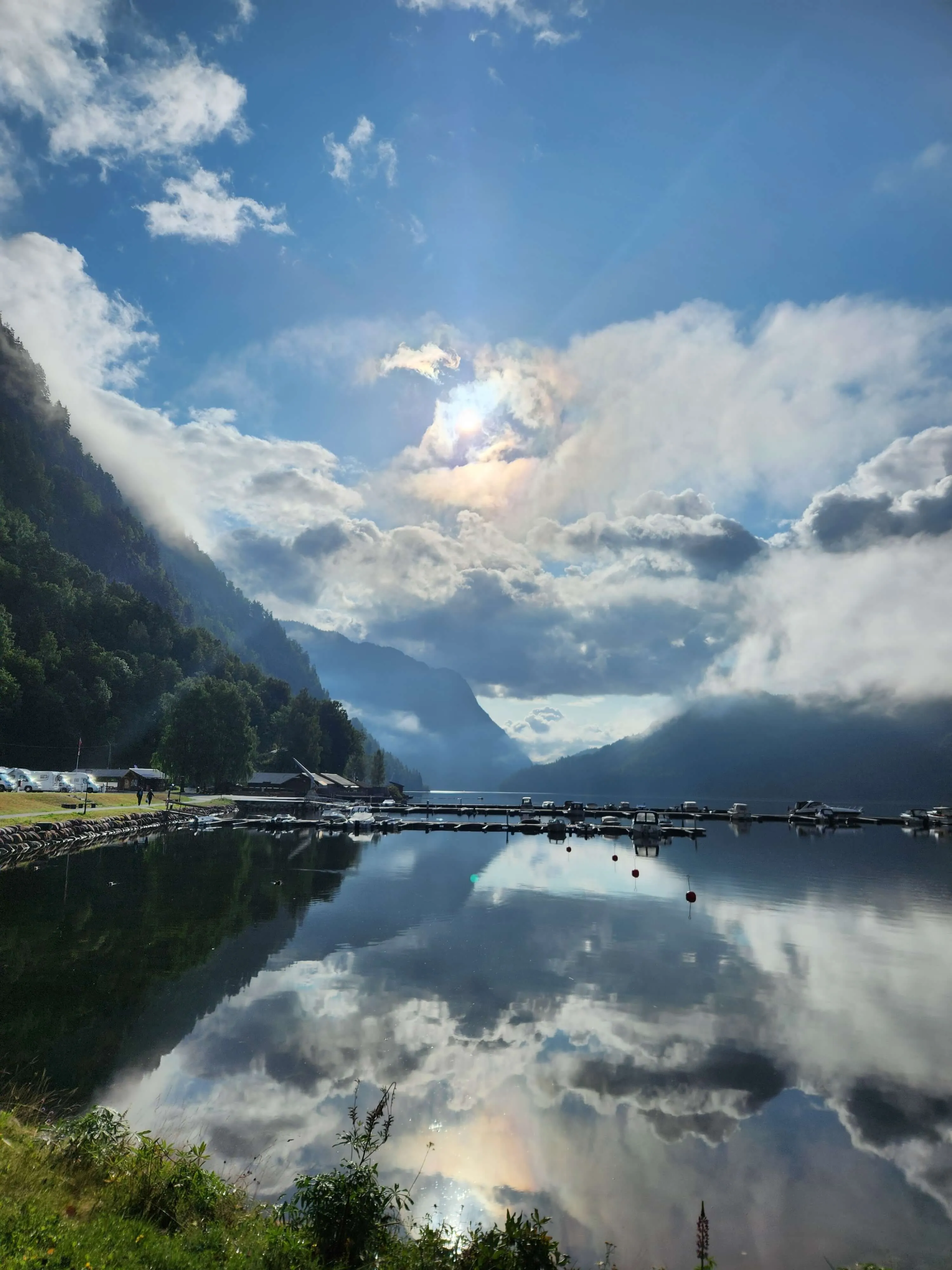 The first place I stopped for the night in Norway, in a valley with a magical view in the morning, forests up on the mountains of the valley, a pier with small boats and the water is still with the sun reflecting on the water.