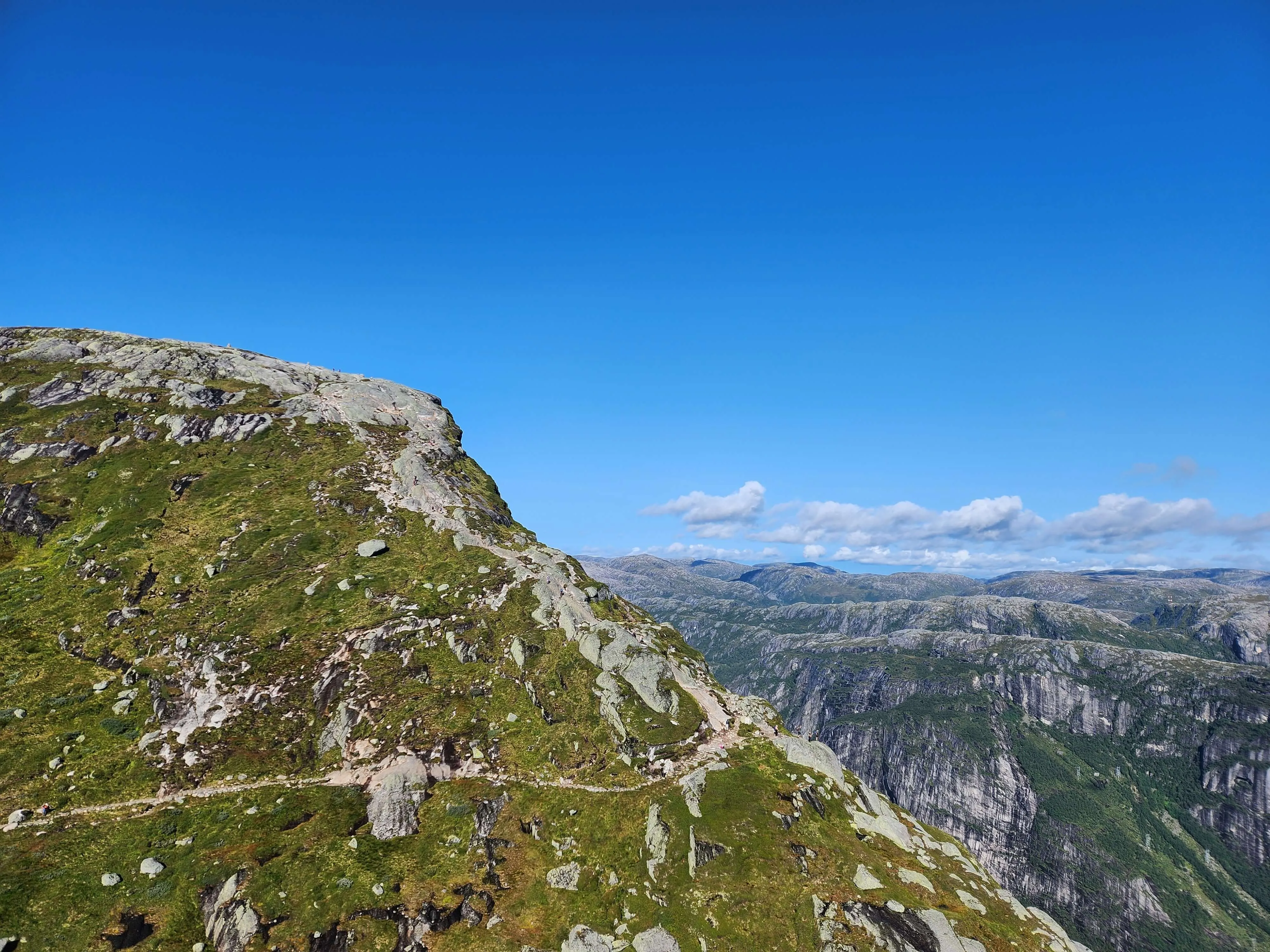 A cliff overlooking the trail running along the second mountain to traverse towards the Kjeragbolt hiking destination